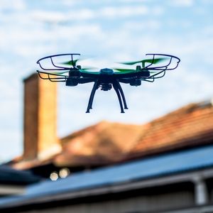 Drone flying with house in background.