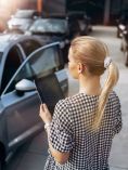Woman holding a tablet and looking at a car.