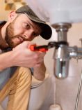 Man using wrench on sink pipe
