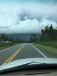 Car driving on road with storm in the distance.