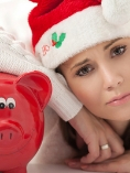 A woman in a Santa hat leaning on a red piggy bank