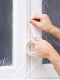 Person covering windows in plastic